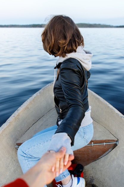 Volg mij naar de boot op het meer. De hand van de donkerbruine vrouw die vriend houdt