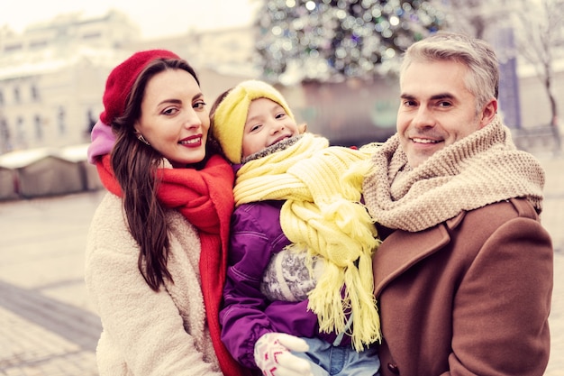 Volg ons. Mooie jonge vrouw die zich dichtbij haar familie bevindt tijdens het samen wandelen