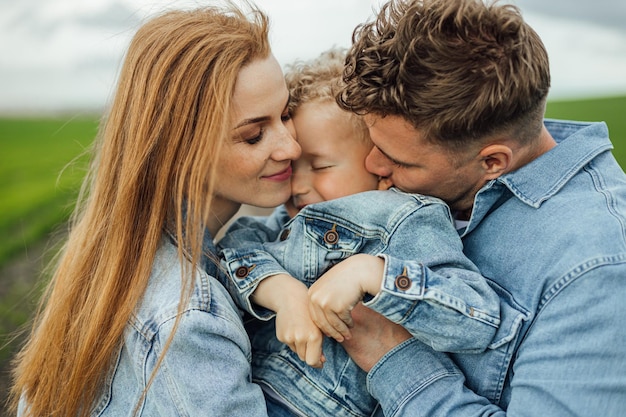 Foto volgroeide jonge familie schoot in denim vrijetijdskleding rond in het park, hand in hand op warme lentedag