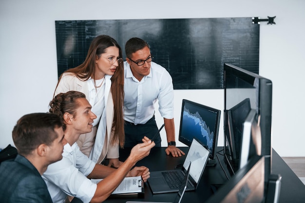 Volgt de grafieken Team van effectenmakelaars werkt in een modern kantoor met veel beeldschermen