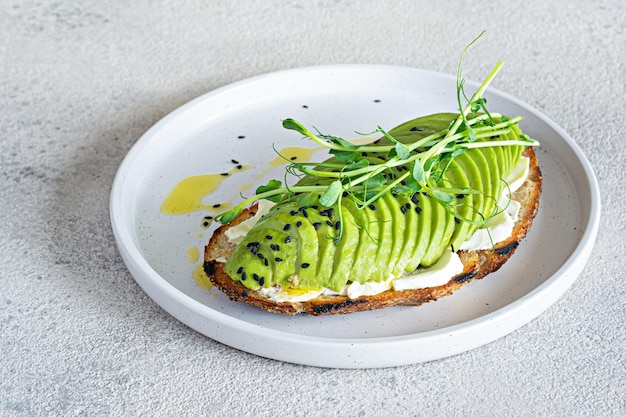 Volkoren avocadotoost met roomkaas, zwarte sesamzaadjes, olijfolie en microgreens