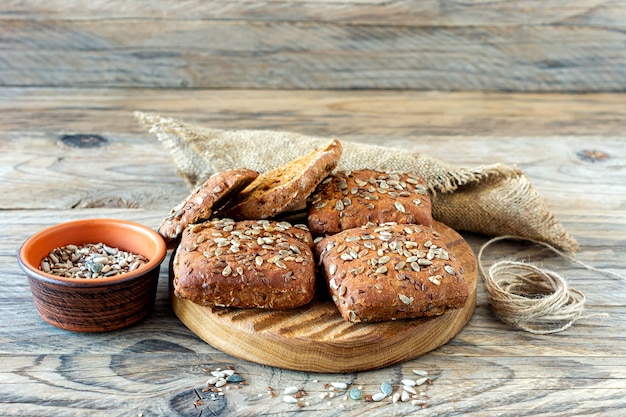 Volkoren brood broodjes met zaden op een houten ondergrond.