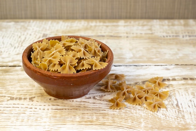 Volkoren donkere pasta bogen op bruine plaat op een ruwe houten lichte achtergrond met geselecteerde focus