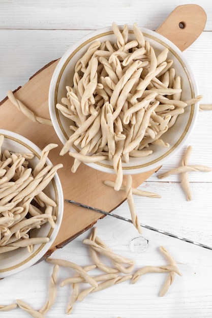 Volkoren tarwe rauwe Apulische pasta genaamd Pizzarieddi of maccaruni op een keramische plaat op witte houten tafel