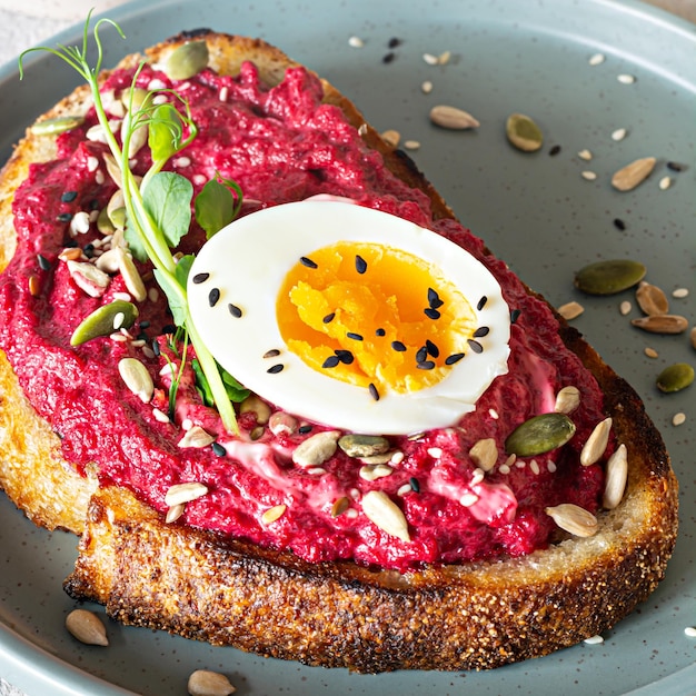 Volkoren toast met bietenhummus, zaden, ei en microgreens (kiemkiemen)