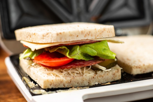 Volkoren toastsandwich met salami en kruiden in een close-up van een tosti-ijzer