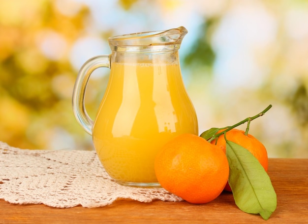 Volle kruik jus d'orange op houten tafel op lichte achtergrond