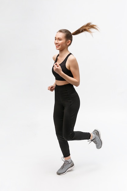 Volle lengte foto van een sport vrouw die in de studio loopt