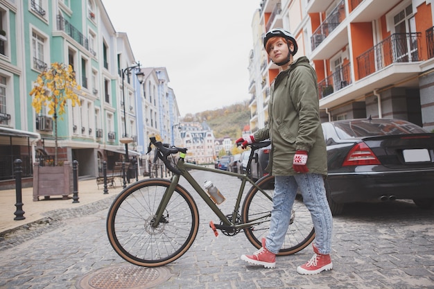 Volle lengte shot van een jonge vrouw die de straat oversteekt met haar fiets