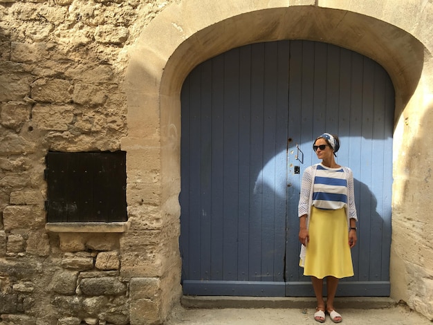 Foto volle lengte van een vrouw die tegen een oud gebouw staat
