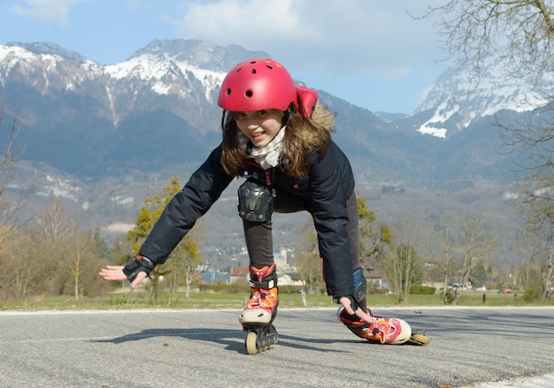 Volle lengte van meisje rolschaatsen op de weg tegen de berg