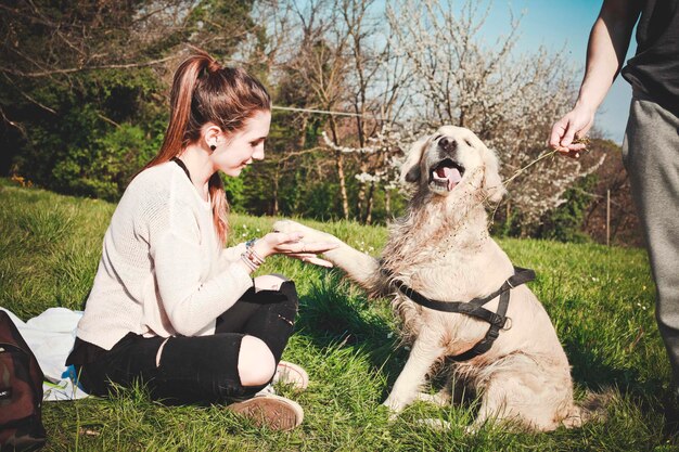 Foto volle lengte van vrouw die met hond speelt door vriend op grasveld