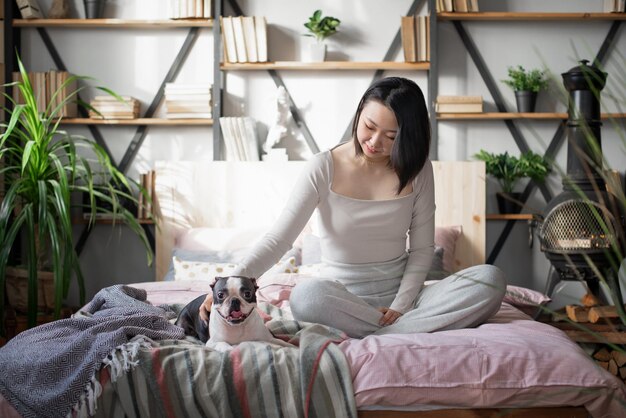 Volle lengte van vrouw die op bed zit