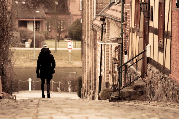 Volle lengte van vrouw die op een pad loopt bij een gebouw in de stad