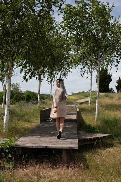 Volle lengte van vrouw die op gras tegen bomen staat