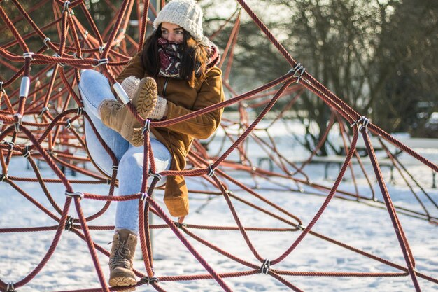 Volle lengte van vrouw die op touwen rust in een met sneeuw bedekt park
