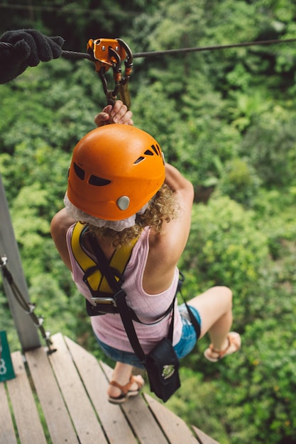 Foto volle lengte van vrouw die op zipline over bomen hangt