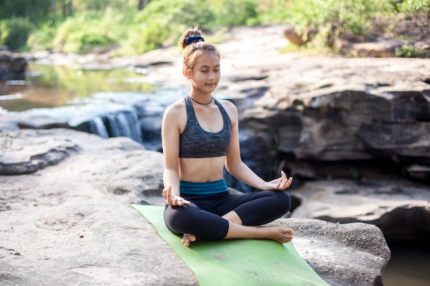 Volle lengte van vrouw die yoga doet op een rots in het bos