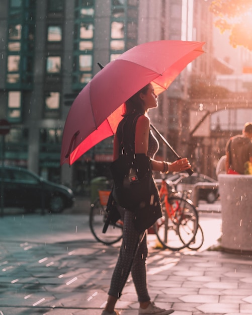 Foto volle lengte van vrouw met paraplu die in de stad loopt tijdens het regenseizoen