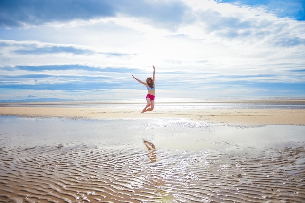 Volle lengte van vrouw springen op het strand tegen de lucht