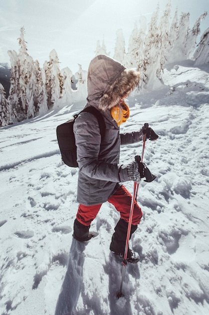 Volle lengte van vrouw wandelen op besneeuwde berg tegen de lucht