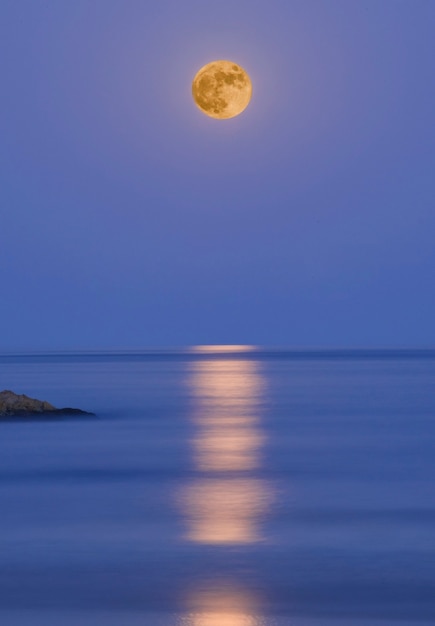 Volle maan boven de zee met reflecties in het water