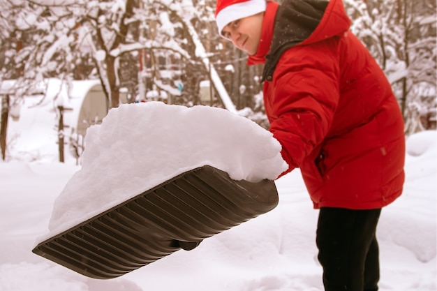 Volle schop sneeuw Man verwijdert sneeuw met grote plastic schop met houten handvat