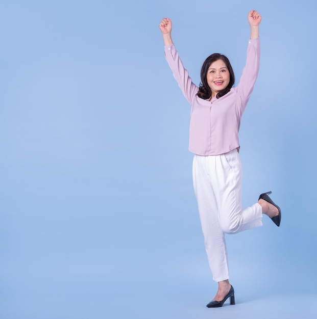 Volledig beeld van een Aziatische vrouw van middelbare leeftijd op een blauwe achtergrond