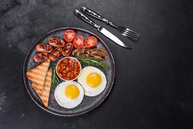 Volledig engels ontbijtboon gebakken eieren geroosterde worstjes tomaten champignons op een donkere betonnen tafel met geroosterd brood