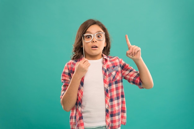 Volledig geïnspireerd kind schoolmeisje kreeg een idee jeugdgeluk kind in een goed en positief humeur ziet er slim uit in een bril klein meisje geïnspireerd door casual mode gelukkig kind in een grappige feestbril