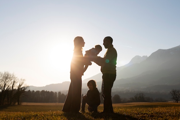 Volledig geschoten familiesilhouet in de natuur bij zonsondergang