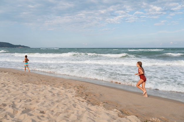 Foto volledig geschoten kleine kinderen die plezier hebben op het strand