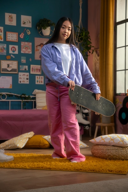 Foto volledig geschoten smileymeisje met skateboard binnenshuis