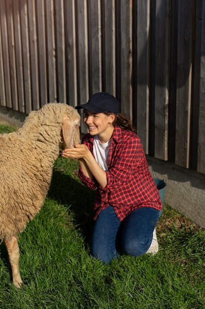 Foto volledig geschoten smileyvrouw die schapen aait