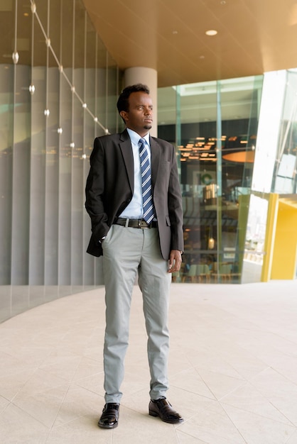 Volledig lengteportret van Afrikaanse zakenman die kostuum en stropdas in openlucht in stad draagt