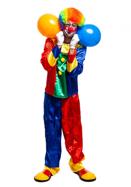 Foto volledig lengteportret van een mannelijke clown in de bos van de kostuumholding ballons die op witte achtergrond wordt geïsoleerd