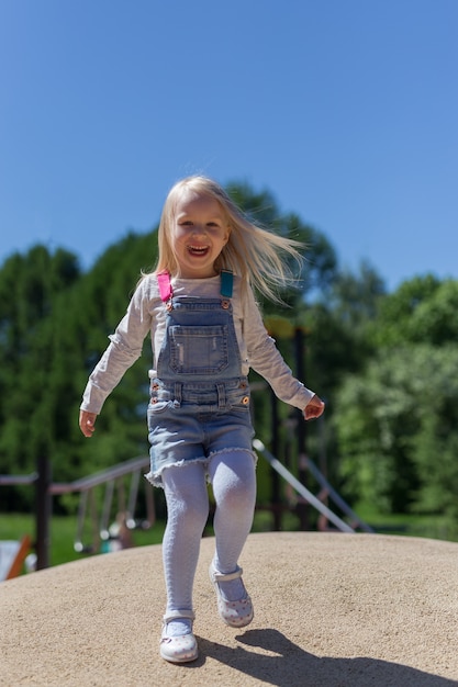 Volledig lengteportret van gelukkig blonde 4 jaar meisjes het spelen op speelplaats in openlucht tegen groene bomen en blauwe hemel