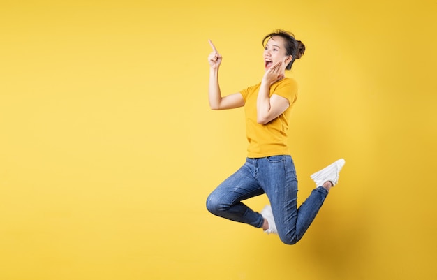 Volledig lengteportret van vrolijk meisje dat omhoog springt geïsoleerd op gele background