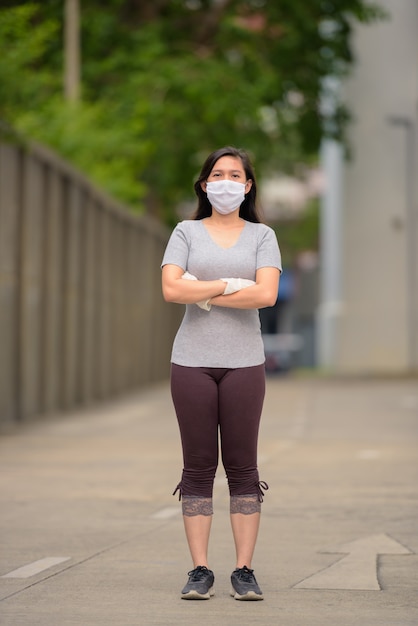 Volledig lichaam dat van jonge Aziatische vrouw is ontsproten met masker en handschoenen voor bescherming tegen de uitbraak van het coronavirus