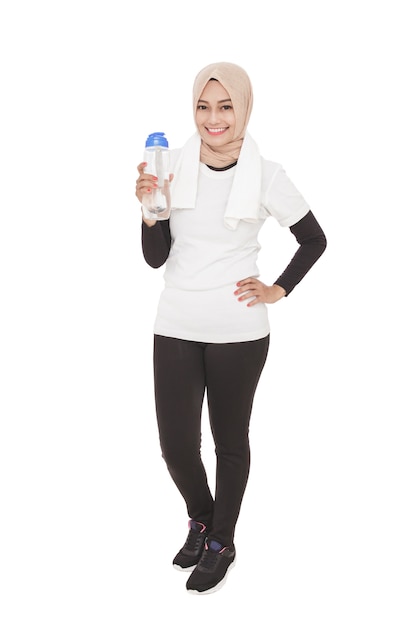 Volledig lichaamsportret van Aziatische sportieve vrouw die hijab draagt die een fles mineraalwater houdt