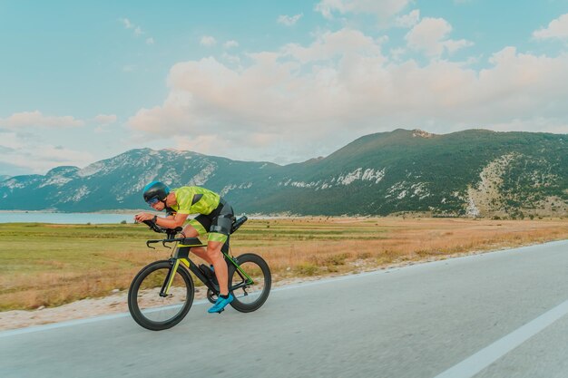 Volledig portret van een actieve triatleet in sportkleding en met een beschermende helm op de fiets. Selectieve focus.