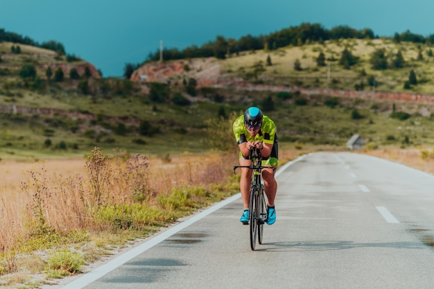 Volledig portret van een actieve triatleet in sportkleding en met een beschermende helm op de fiets. Selectieve focus.