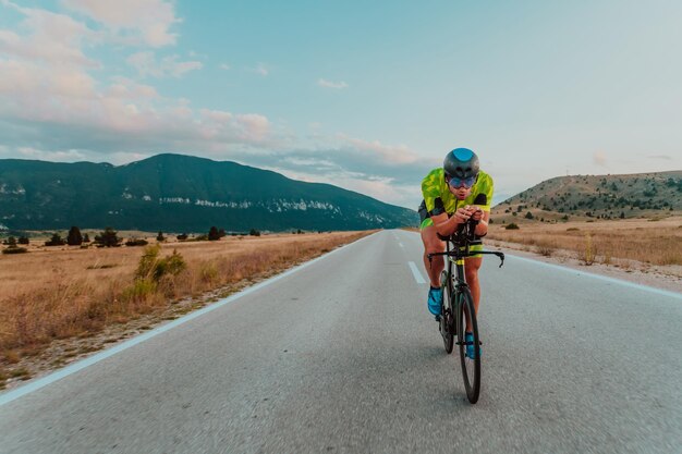 Volledig portret van een actieve triatleet in sportkleding en met een beschermende helm op de fiets. Selectieve focus.