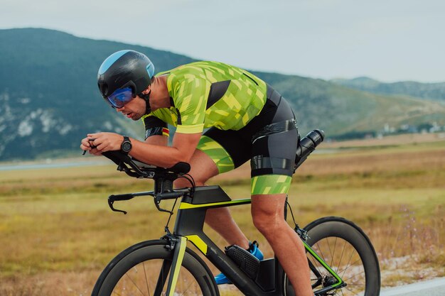 Volledig portret van een actieve triatleet in sportkleding en met een beschermende helm op de fiets. Selectieve focus.
