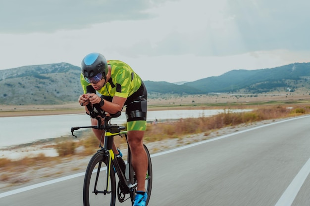 Volledig portret van een actieve triatleet in sportkleding en met een beschermende helm op de fiets. Selectieve focus.