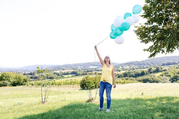 Foto volledig portret van een glimlachende jonge vrouw die op een landschap staat