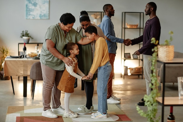 Volledig portret van een grote Afro-Amerikaanse familie die aan het chatten is terwijl ze gasten verwelkomt voor een etentje ...