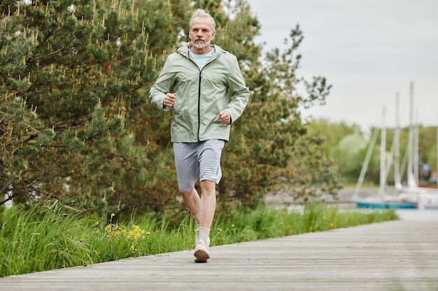 Volledig portret van een knappe volwassen man die buiten naar de camera rent in het parkstadsgebied, kopieer s