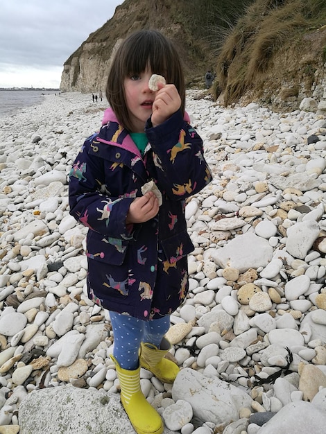 Volledig portret van een meisje met een kiezel op het strand