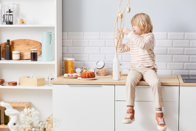 Volledig portret van een schattige kleine jongen die het huis decoreert voor Pasen in een gezellige kopieerruimte in de keuken